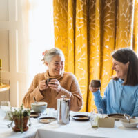 Two female clients smiling and talking over brunch at the Combe Grove