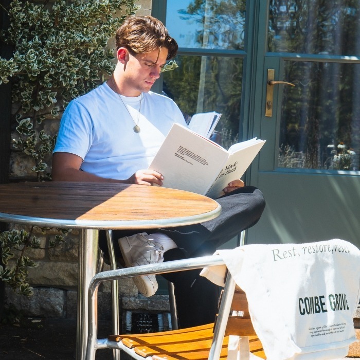 Man reading book outside his Combe Grove room